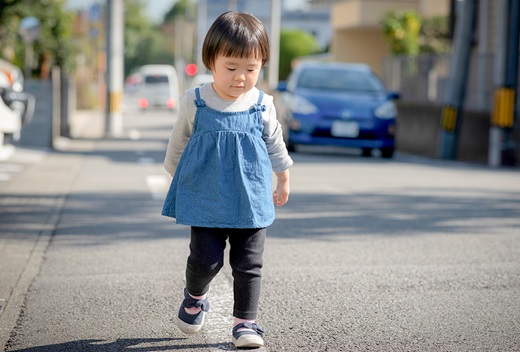クルマ通りのある道を歩く女の子