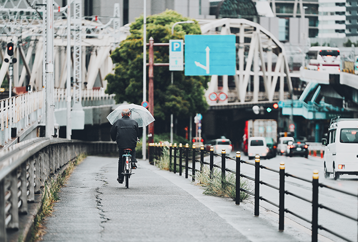 自転車で傘さし運転する大人