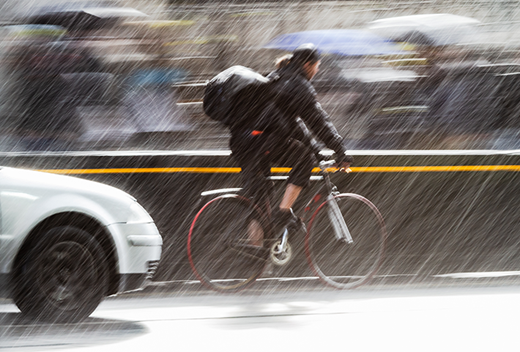 雨の中自転車をこぐ男性