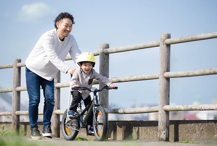 自転車に乗る子どもと補助する父親