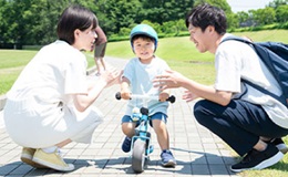 自転車に乗る子どもと見守る親