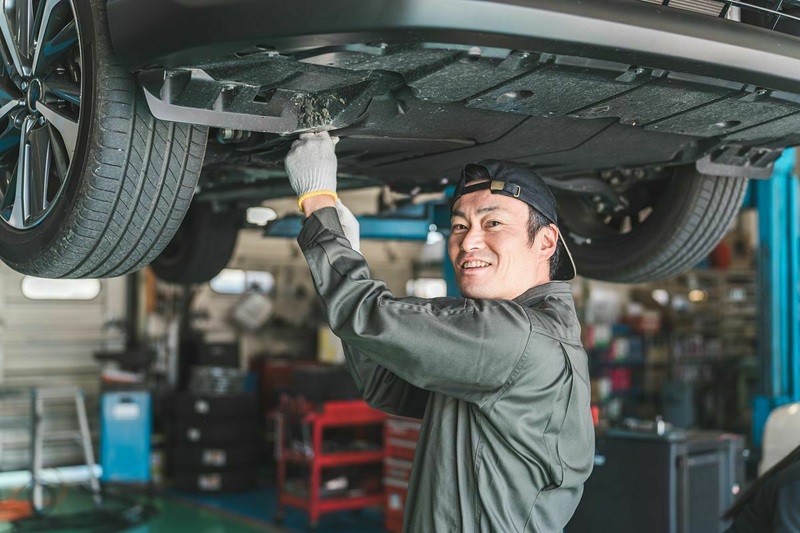 クルマのアンダーカバーを外して整備・点検する整備士